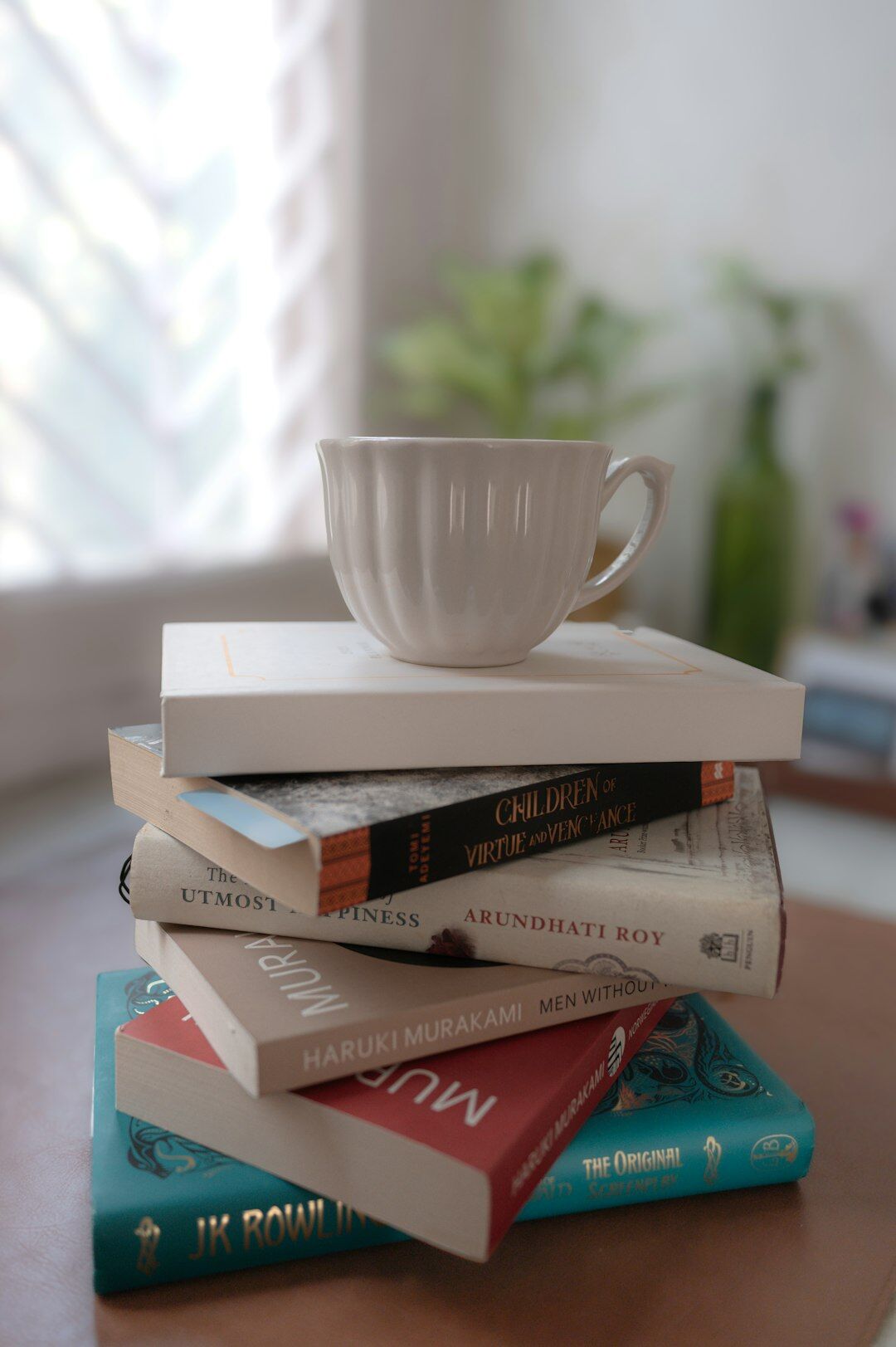 Stack of hardcover books with a cup of coffee on top of a table
